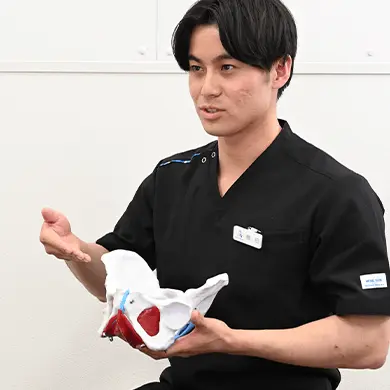 写真：骨盤の模型も持って説明をする整体師