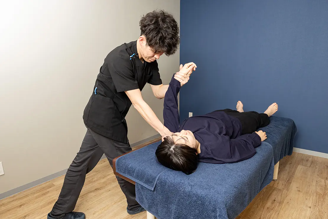 写真：女性の肩のマッサージをする整体師